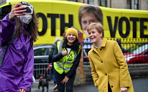 スコットランド議会選の候補者と投票所の前で記念撮影するスタージョン行政府首相㊨=ロイター