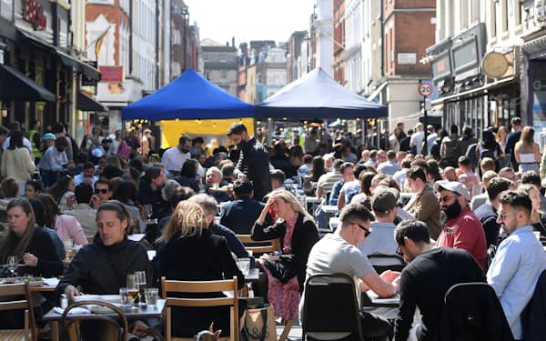 解禁された飲食店の屋外席に繰り出す英市民（4月24日、ロンドン中心部の繁華街）=ロイター