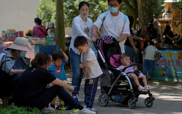 People wearing face masks bring their children tour a public park during the International Children's Day in Beijing, Tuesday, June 1, 2021. China's leaders  have announced it would let all couples have three children instead of two, hoping to counter the rapid aging of Chinese society. (AP Photo/Andy Wong)