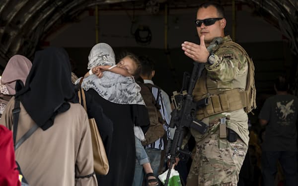 カブールの空港で、アフガニスタンから退避する女性らを米軍機に誘導する兵士（24日）＝ＡＰ