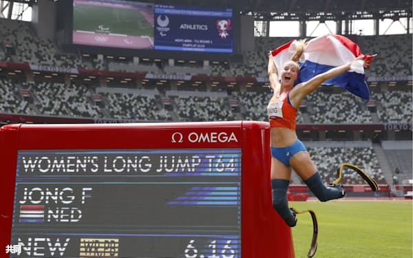世界新記録での優勝を表す掲示板の横で、飛び上がって喜ぶヨング=共同