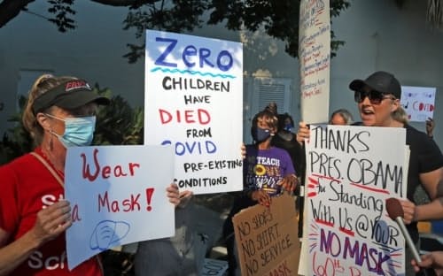 2021年8月10日、米国フロリダ州のブロワード郡教育委員会の外で行われた抗議活動で、マスクの着用を訴える女性（左）に、マスクは不要だと説得を試みるマスク反対派の女性（右）。（PHOTOGRAPH BY AMY BETH BENNETT, SOUTH FLORIDA SUN-SENTINEL VIA AP）