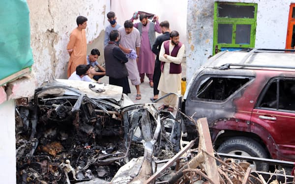 米軍無人機の空爆で大破した車と死亡したアフガニスタン人の親族ら（8月30日、カブール）＝UPI・共同