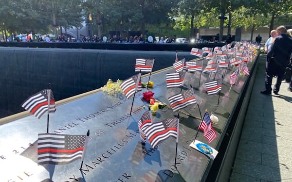 犠牲者の名前を刻んだ石碑には、花やゆかりの品、星条旗が置かれた（11日、ニューヨーク）