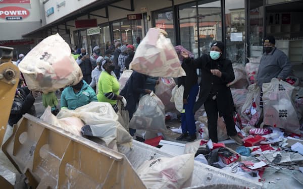 ヨハネスブルクで略奪にあった店舗の片付けをする人々。南アフリカでは暴動や略奪が頻発している＝ＡＰ