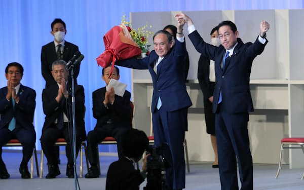 拍手に応える菅首相と自民党の岸田新総裁（29日、東京都港区）