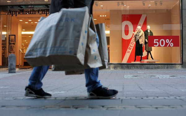 ショッピングバッグを提げて歩く買い物客（ドイツ北部のキール、３月）＝ロイター