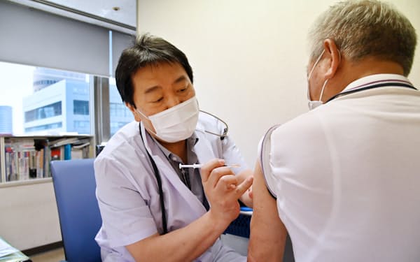 新型コロナウイルスのワクチンを接種する診療所の医師（10日、大阪市北区）
