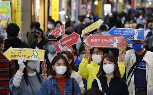 商店街で投票を呼び掛ける若者たち（24日、東京都内）