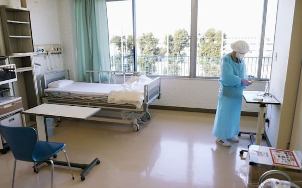 新型コロナウイルス患者の入室を前に、防護具を着用して病床の準備をする看護師（2020年12月22日、東京都三鷹市の杏林大病院）＝共同