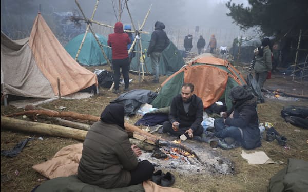 ポーランド国境付近のベラルーシ側で寒さをしのぐ移民ら（11日）=AP