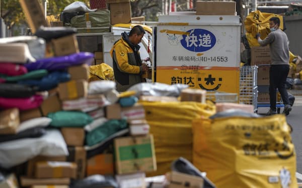 Workers of a private delivery company sort out piling up at a pickup point near a residential apartment buildings in Beijing, Tuesday, Nov. 16, 2021. Chinese data reported Monday showed October retail sales growth weakened compared with the previous month, weakened by anti-coronavirus restrictions and consumer unease over a wave of outbreaks. (AP Photo/Andy Wong)