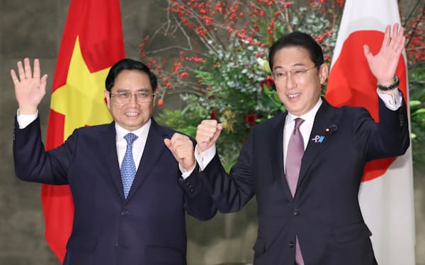 ベトナムのファム・ミン・チン首相㊧を出迎え、ともに手を振る岸田首相（24日、首相官邸）