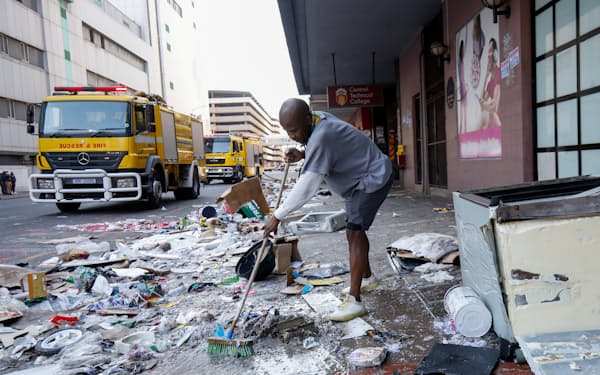 暴動で破壊された店舗の前でがれきを片付けるボランティア（７月１５日、東部ダーバン）＝ロイター