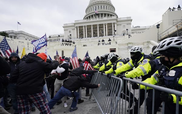 ワシントンの米連邦議会議事堂で警察官のフェンスを突破しようとするトランプ氏の支持者ら（1月）＝AP