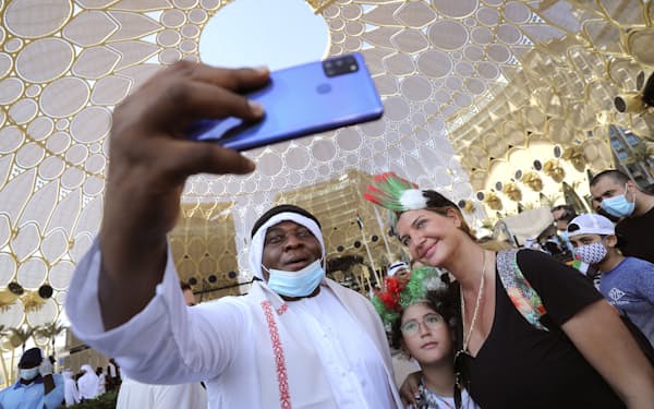 ドバイ万博の会場で、UAE独立50年を祝い、外国人と一緒に自撮りする男性（2日）=AP