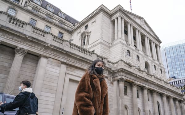 A woman wears a face mask as she walks outside the Bank of England, in the financial district known as The City, in London, Thursday, Dec. 16, 2021. The Bank of England raised interest rates in the United Kingdom on Thursday to combat surging consumer prices, becoming the first central bank among the world's leading economies to do so since the coronavirus pandemic began. The increase in the bank's main rate to 0.25% from the record low of 0.1% was a surprise given the rapid spread of the omicron variant of the coronavirus across the country, which is already hurting many businesses, particularly those in the hospitality sector.(AP Photo/Alberto Pezzali)