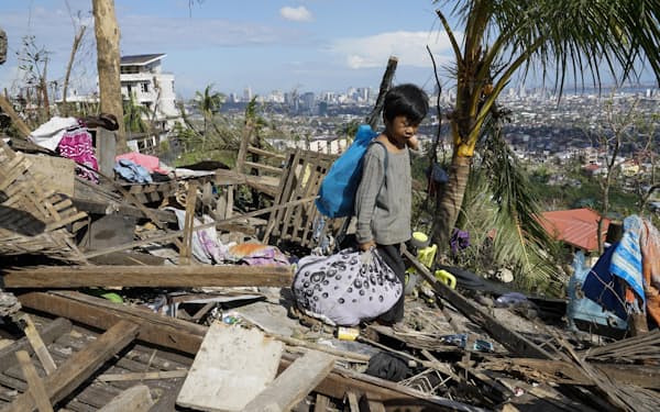 台風で損壊した住宅から持ち物を拾い集める住民＝19日、フィリピン・セブ州（AP）