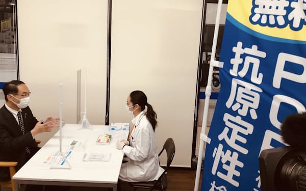 無料PCR検査の仕組みについて薬剤師から説明を受ける埼玉県の大野元裕知事（24日、さいたま市のウエルシア浦和上木崎店）