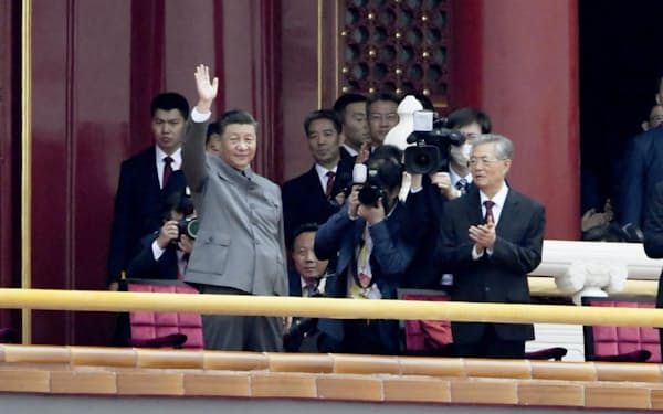 中国共産党創建100年を記念する祝賀大会を終え、参加者に手を振る党総書記の習近平国家主席（左上）。下は毛沢東の肖像画＝7月、北京の天安門（共同）