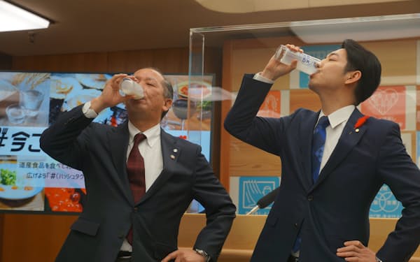 鈴木直道知事㊨がホクレンの西川副会長と牛乳を飲み干した（16日）