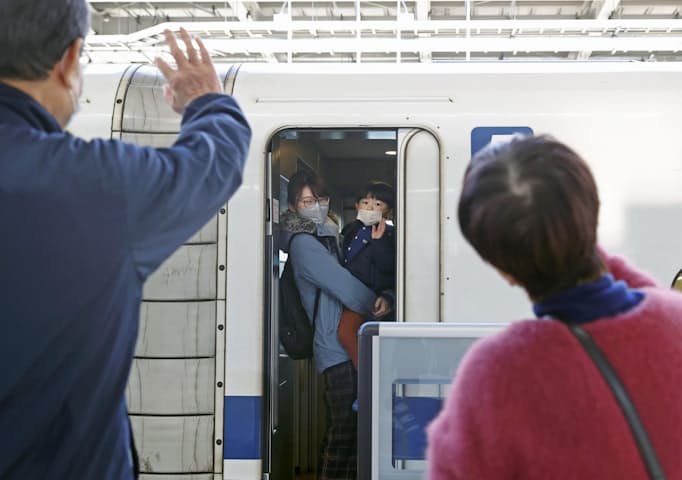JR新大阪駅で新幹線の車内から見送りの祖父母に手を振る親子連れ（3日）=共同