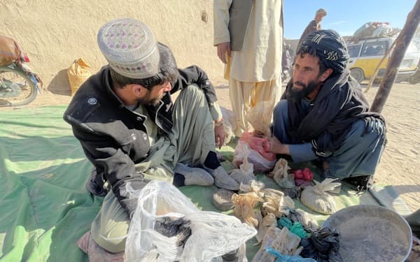 アヘン原料のケシを小袋にわけるアフガニスタンの販売業者（2021年12月、同国南部カンダハル）＝ゲッティ共同