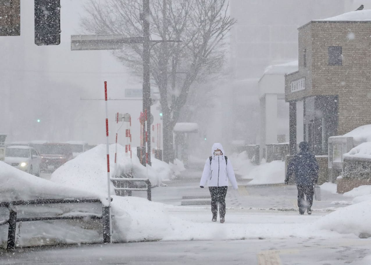 　雪が降りしきる中、青森市内を歩く人たち（12日午後2時21分）=共同
