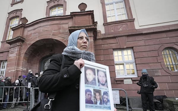 13日、ドイツ・コブレンツの裁判所前で、シリアで亡くなった5人の兄弟の写真を手にするシリア人の女性＝AP