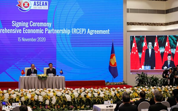 Vietnam's Prime Minister Nguyen Xuan Phuc (L) sits next to Minister of Industry and Trade Tran Tuan Anh as they watch a screen showing Chinese Minister of Commerce Zhong Shan (R) signing next to Chinese Premier Li Keqiang during the virtual signing ceremony of the Regional Comprehensive Economic Partnership (RCEP) Agreement during the 37th ASEAN Summit in Hanoi, Vietnam November 15, 2020. REUTERS/Kham