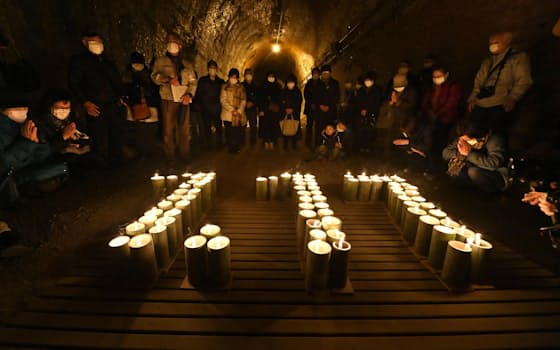 神戸市兵庫区の「湊川隧道」で行われた追悼集会で、「1・17」の形に並べられた灯籠を前に黙とうする人たち（15日午後）=共同