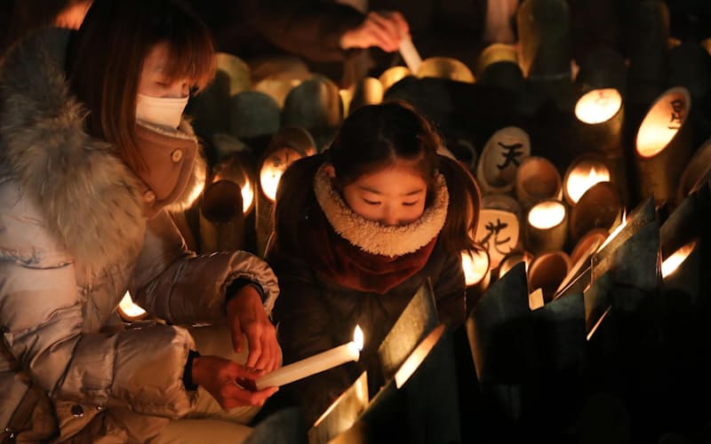阪神大震災から27年を迎え、灯籠に明かりをともす人たち（17日午前、神戸市中央区の東遊園地）=柏原敬樹撮影