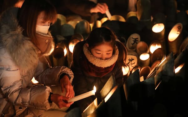 阪神大震災から27年を迎え、灯籠に明かりをともす人たち(17日午前、神戸市中央区の東遊園地)=柏原敬樹撮影