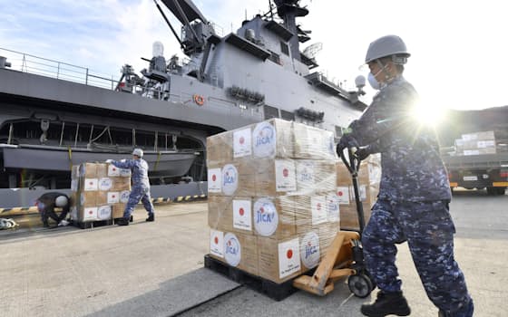 輸送艦「おおすみ」に、トンガへの支援物資を積み込む自衛隊員ら（24日午前、広島県呉市の海上自衛隊呉基地）=共同