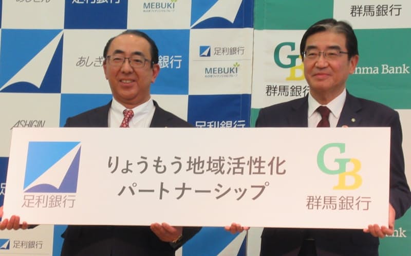 記念撮影をする群馬銀行の深井頭取㊨と足利銀行の清水頭取(24日、群馬県桐生市) 記念撮影をする群馬銀行の深井頭取㊨と足利銀行の清水頭取(24日、群馬県桐生市)