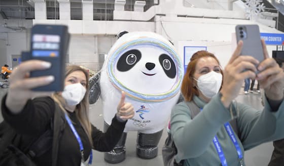 　メインメディアセンターに現れた北京冬季五輪のマスコットを写真に収める関係者ら=24日、北京（共同）