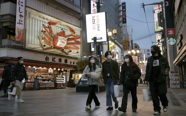 27日にまん延防  止等重点措置が適用される大阪府の繁華街を歩くマスク姿の人たち（26日午後）＝共同