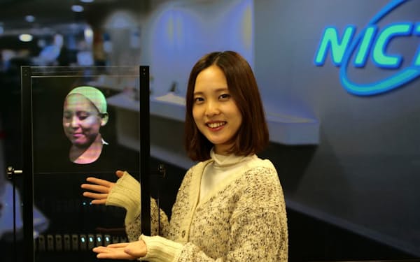 NICTが開発した透明ディスプレーに、顔の3D映像を表示している様子。左が透明ディスプレーで、右がモデル本人（写真：NICT）