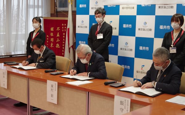 福井市の東村新一市長（中央）らが連携協定に署名した（８日、福井市役所）