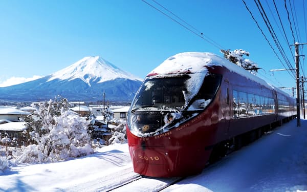 富士山をバックに車体の屋根に雪を載せて走る富士山ビュー特急