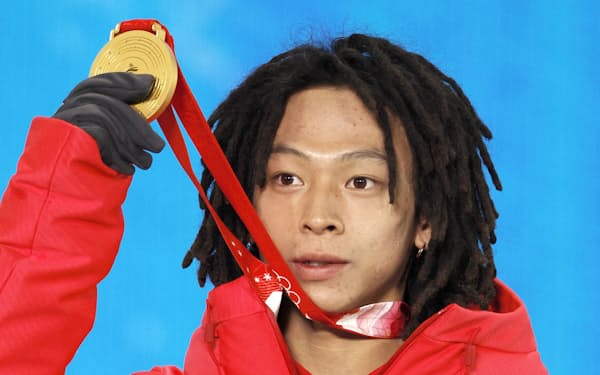 スノーボード男子ハーフパイプのメダルセレモニーで金メダルを掲げる平野歩夢＝共同