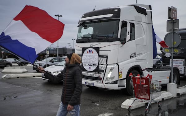 車両デモに参加するトラックの近くでフランス国旗を振る支援者（11日、仏リヨン）＝AP