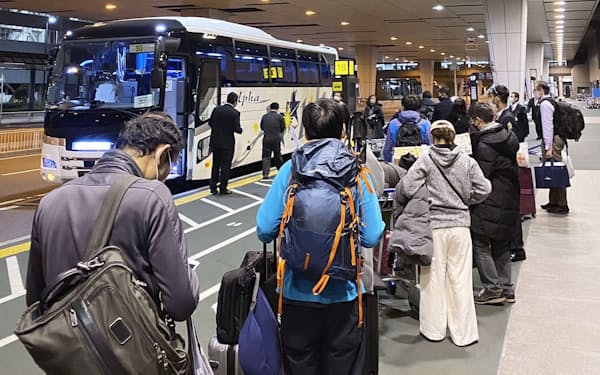 指定施設に向かう専用バスに乗車する帰国者ら（21年12月、成田空港）＝共同