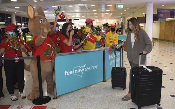 Passengers are welcomed as they arrive at Sydney International Airport in Sydney, Monday, Feb. 21, 2022. International tourists and business travelers began arriving in Australia with few restrictions for the first time in almost two years after the government lifted some of the most draconian pandemic measures of any democracy in the world. (Dean Lewins/AAP Image via AP)