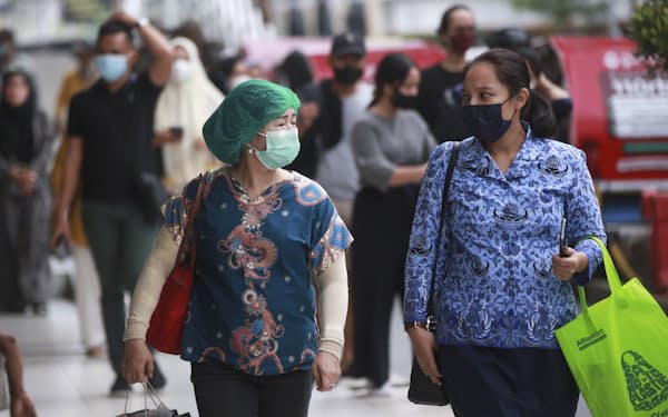 People wearing masks to prevent the spread of the coronavirus chat as they walk at a bus station in Medan, North Sumatra, Indonesia, Thursday, Feb. 17, 2022. (AP Photo/Binsar Bakkara)