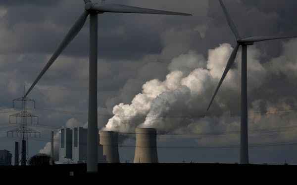 あらゆる産業が「排出ゼロ」実現のプロセスを模索する（ドイツの風力発電所越しに見える石炭火力発電所）＝ロイター