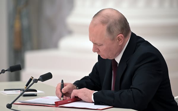 21日、モスクワの大統領府で親ロシア派占領地域の独立承認の文書に署名するプーチン大統領=AP