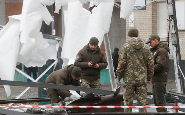 24日、キエフに着弾したミサイルの残骸を調べる警察官＝ロイター