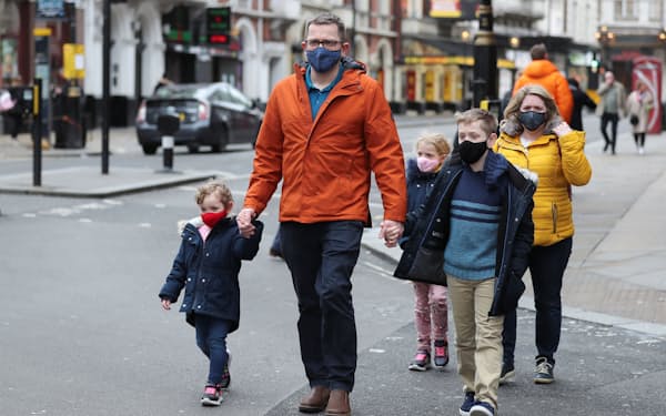 20日、マスクを着用してロンドン市内を歩く人々=ロイター
