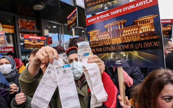 イスタンブールでのデモで、請求書を掲げて電気代などの高騰に抗議する女性=ロイター